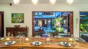 Un espace repas avec vue sur une piscine et des sièges d’extérieur.