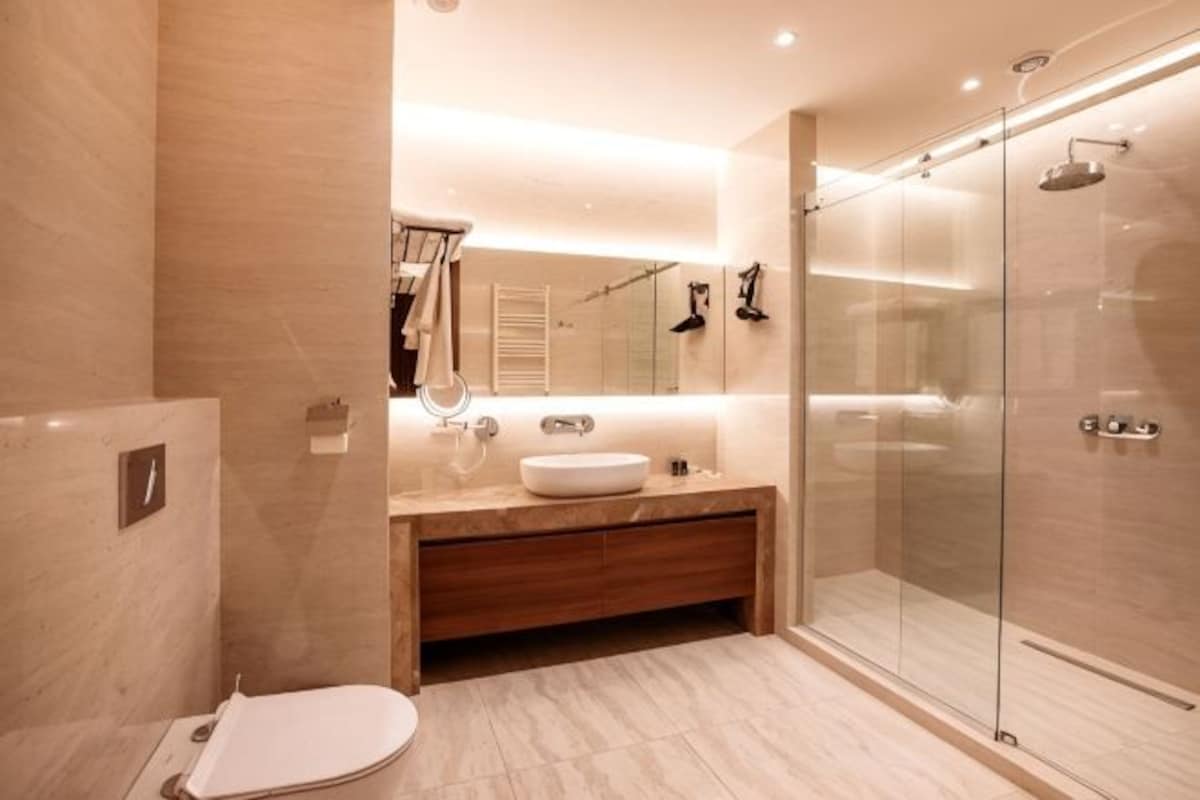 A modern bathroom with a glass shower enclosure, a wooden vanity, and a white sink.
