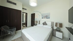 A hotel room with a bed, bedside tables, a TV, a wardrobe, and a chair. - Luxury 4BR Villa With Private Garden (Dubai)
