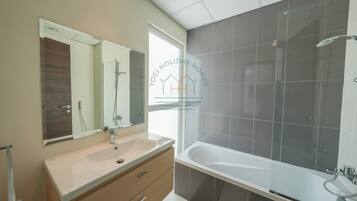 Un bagno moderno con uno specchio grande, una vasca e un mobile lavabo.