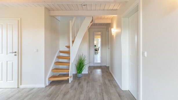 A hallway with a wooden staircase, a potted plant, and a door leading to another room. - Vacation home "Seemannsnest" in Dagebüll for up to 4 people (Dagebüll)