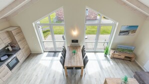 A modern kitchen with a built-in oven and a dining area with a wooden table and chairs. - Vacation home "Seemannsnest" in Dagebüll for up to 4 people (Dagebüll)