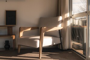 Una sedia moderna con gambe in legno e seduta imbottita, posizionata vicino a una finestra con tende.