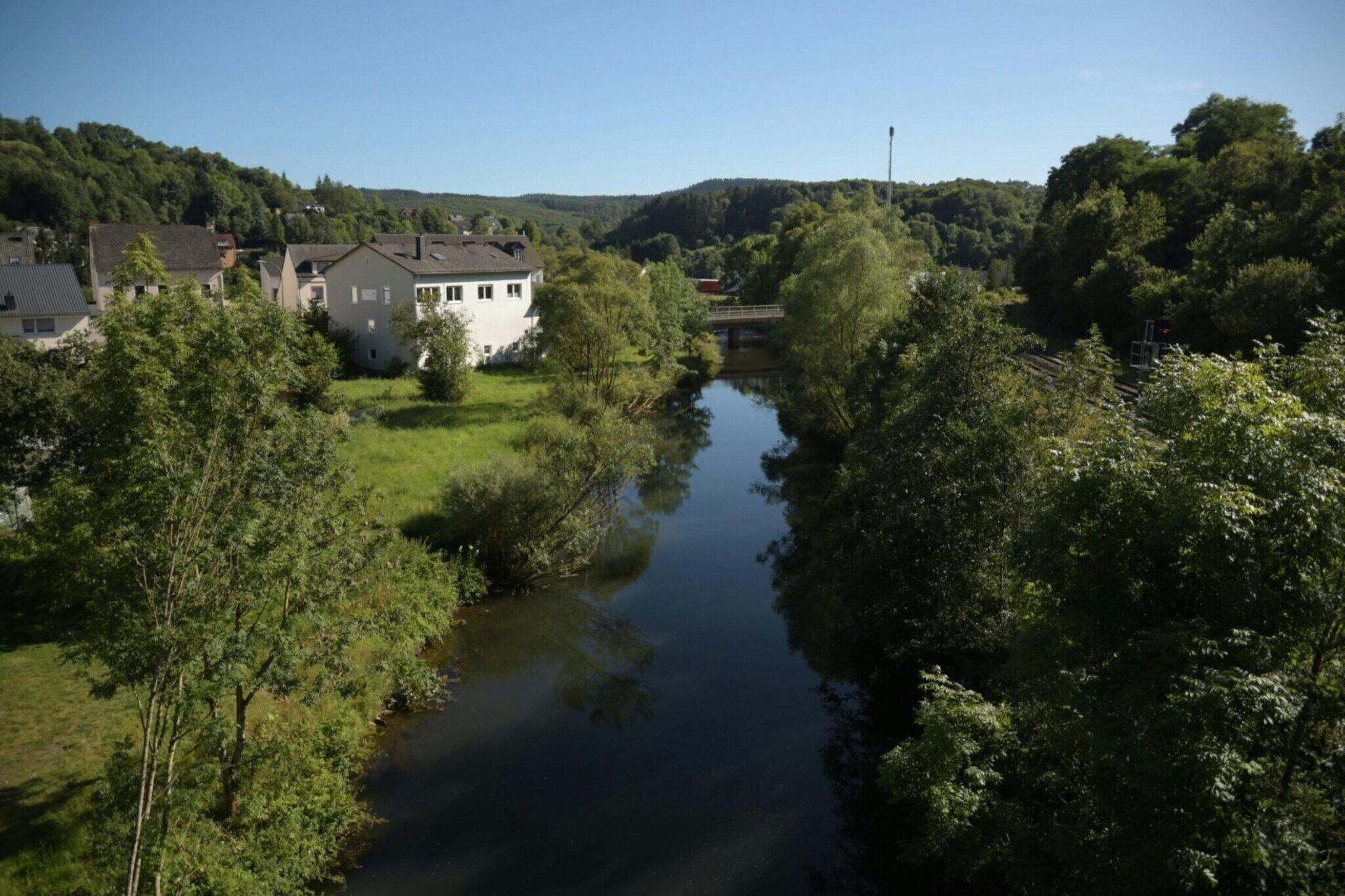 Ein Fluss fließt durch ein Wohngebiet, beidseits des Flusses stehen Häuser.