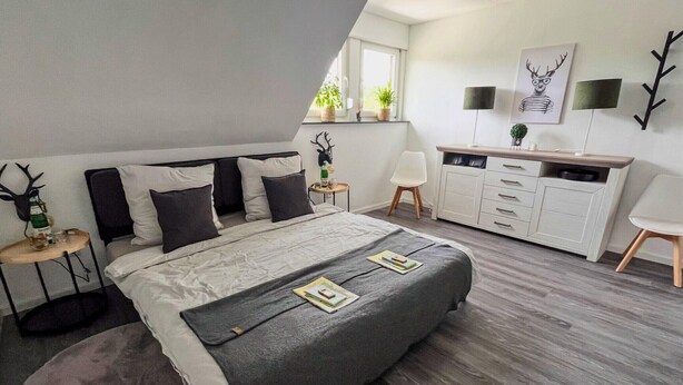 Un dormitorio moderno con una cama grande, un escritorio y una silla.