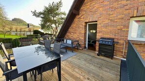 Un patio al aire libre con pared de ladrillo, una parrilla y una mesa con sillas.