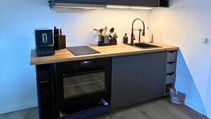 Une cuisine moderne équipée d’un four encastré, d’un évier et d’un plan de travail agrémenté d’un bloc à couteaux et d’autres ustensiles.