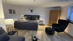 Une chambre à coucher moderne avec un lit, des lampes de chevet, une armoire en bois, une chaise et une petite table sur laquelle est posée une plante.