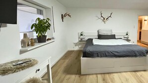 A modern bedroom with a bed, bedside tables, a potted plant, and wall-mounted deer antlers. - Guest rooms Eifelglück in Pelm (Pelm)