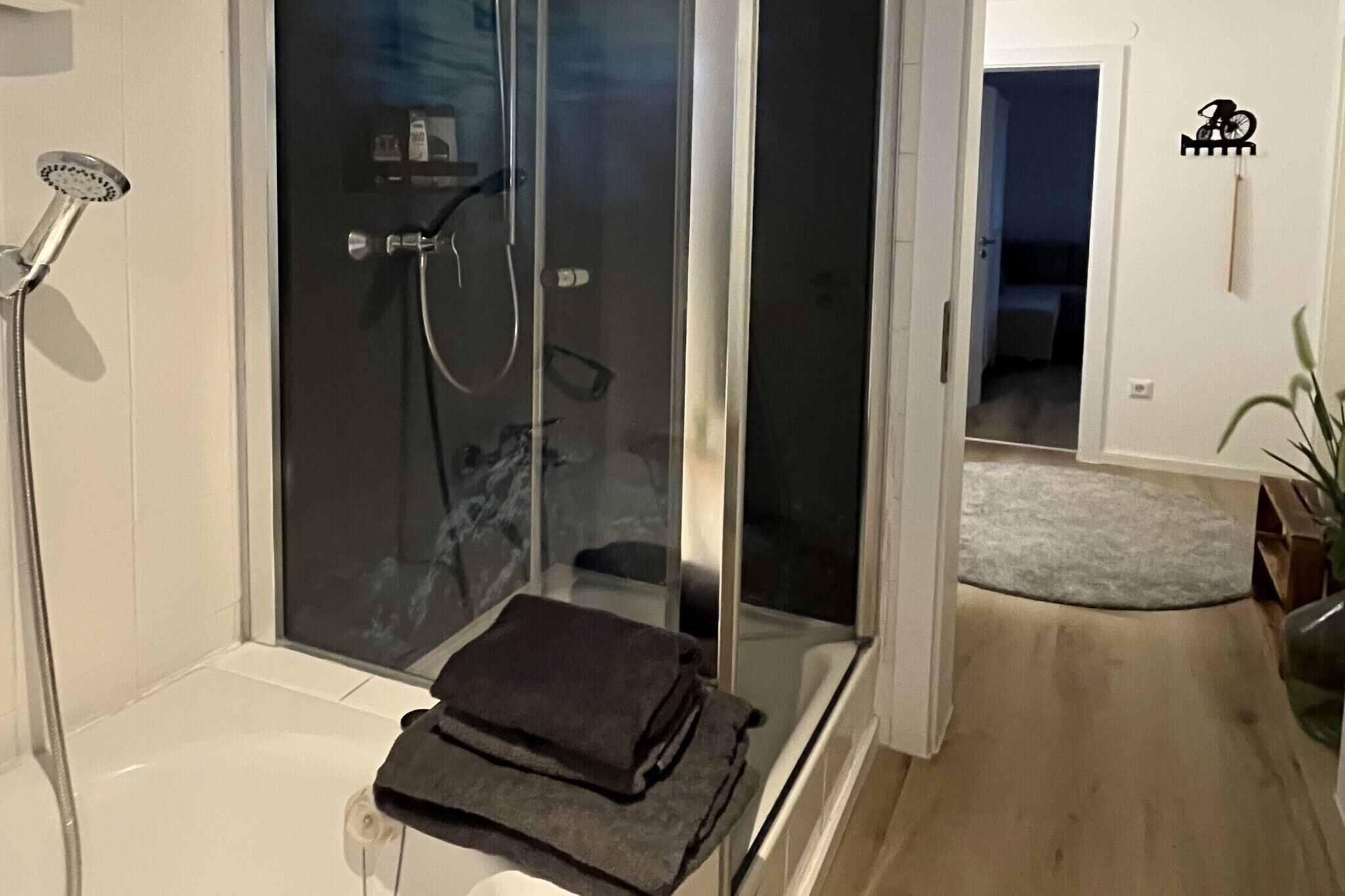 Un bagno moderno con cabina doccia in vetro, water e porta asciugamani.