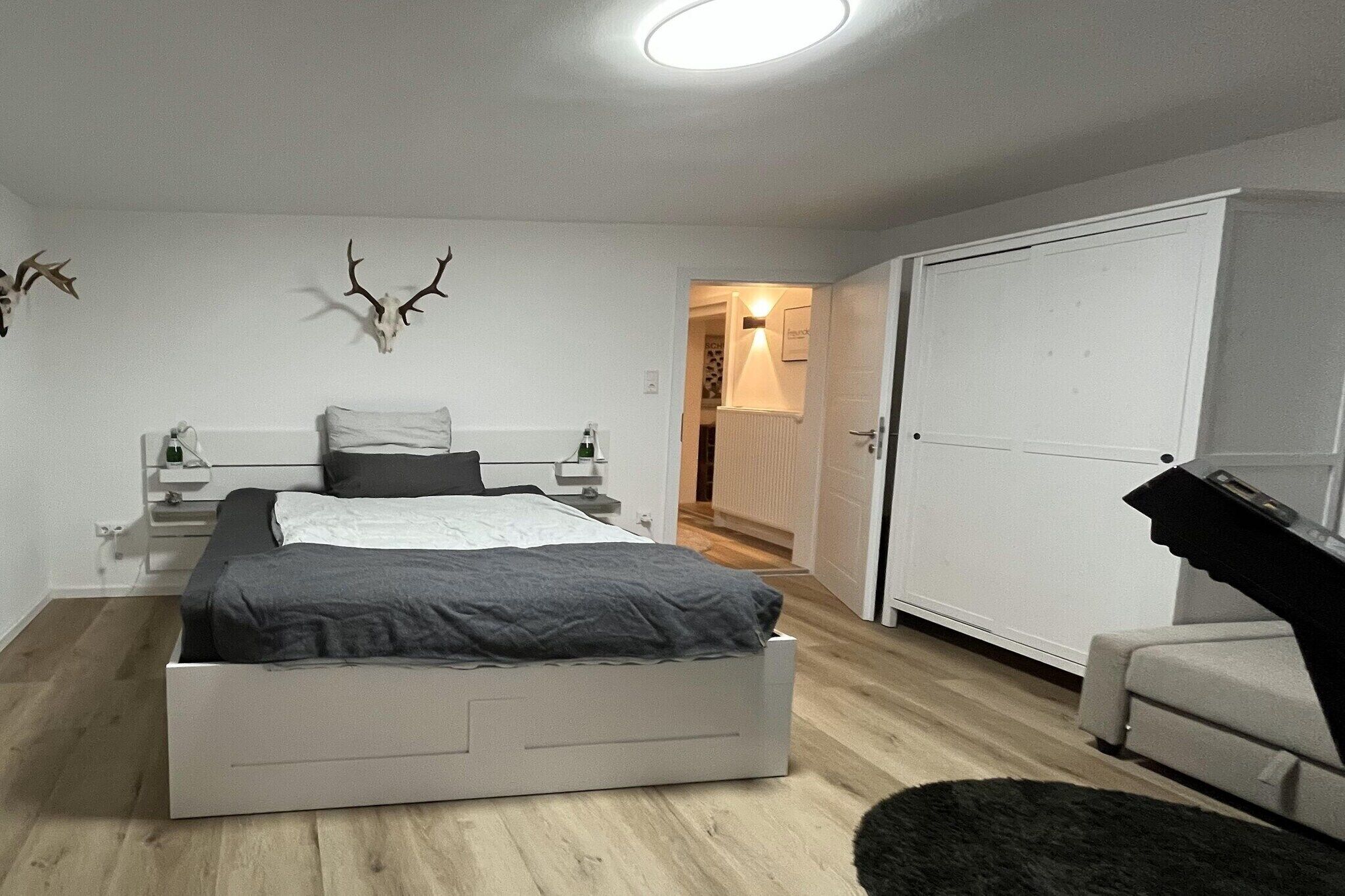 Ein Schlafzimmer mit einem Bett, Nachttischen, einem Kleiderschrank und einer Dekoration mit einem Hirschschädel.