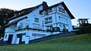 A two-story house with a balcony and a covered porch. - Guest rooms Eifelglück in Pelm (Pelm)