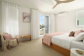 A bedroom with a bed, a chair, a bench, a painting, and a view through a door.