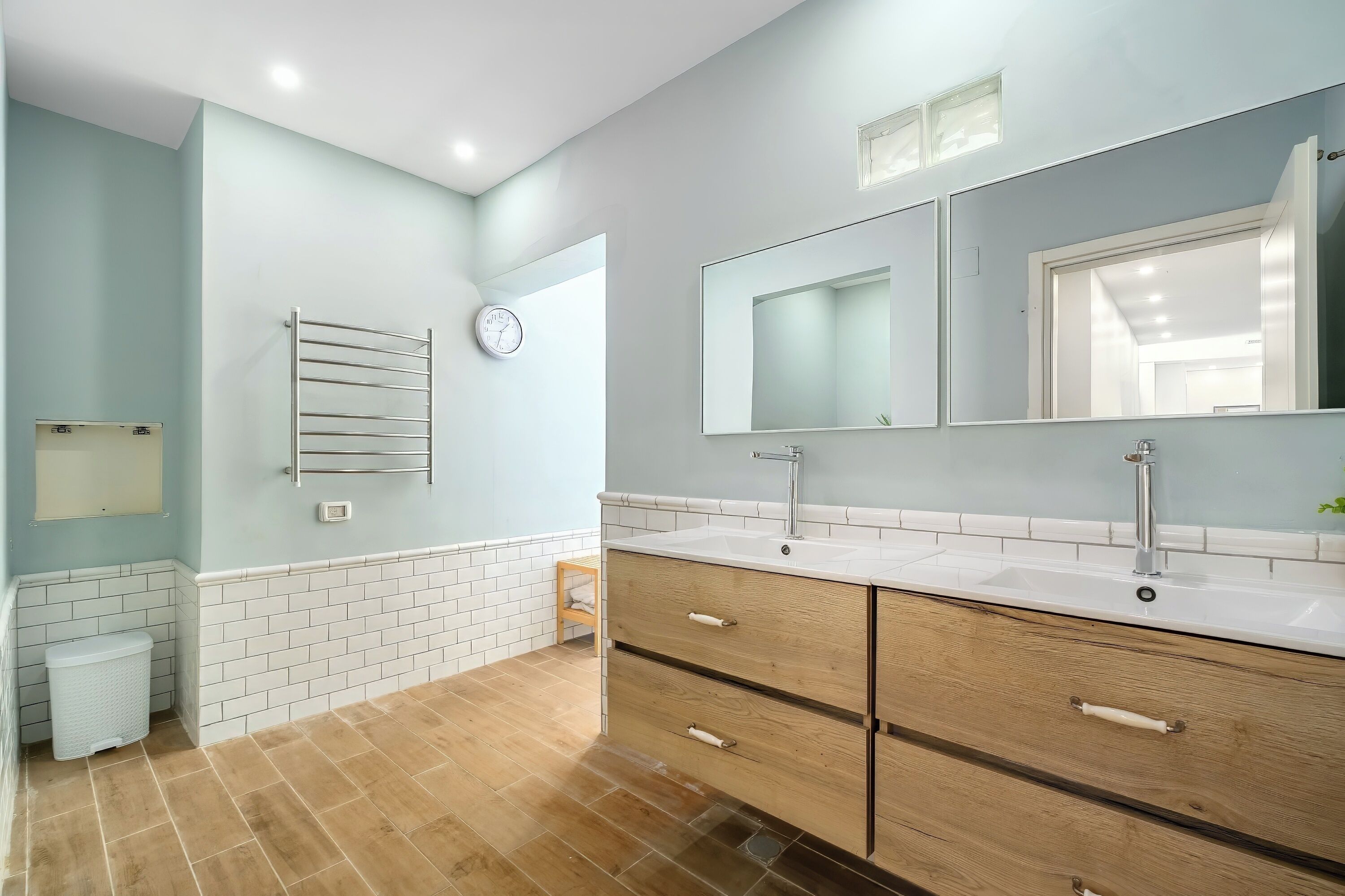 A modern bathroom with two sinks, a large mirror, and a towel rack.