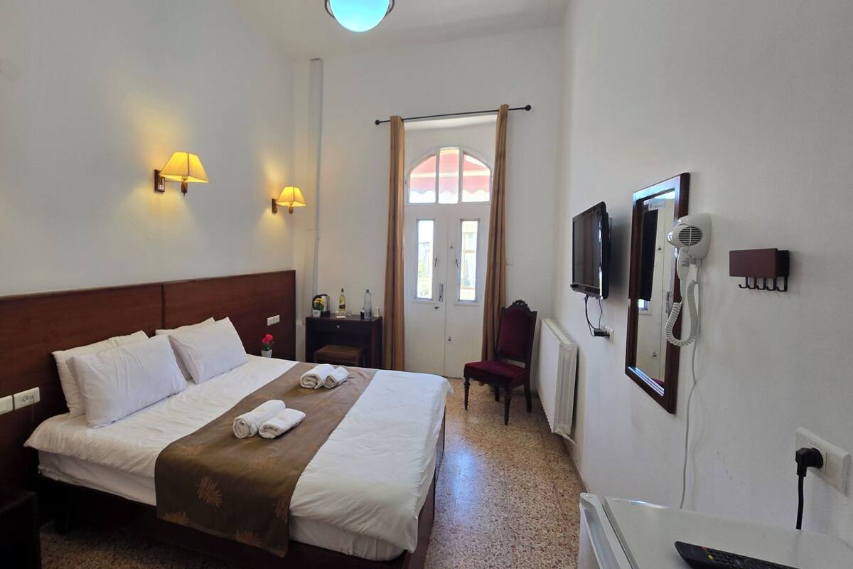 A hotel room with a large bed, two bedside lamps, a TV, a hairdryer, and a telephone.