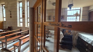 A church interior with wooden pews, a wooden altar, and a cross on the wall.