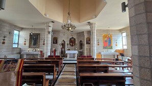 A church interior with wooden pews, a central altar, and religious artwork on the walls.