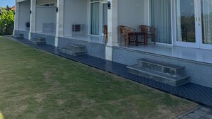 A modern house with a covered porch, large sliding glass doors, and a well-maintained lawn.