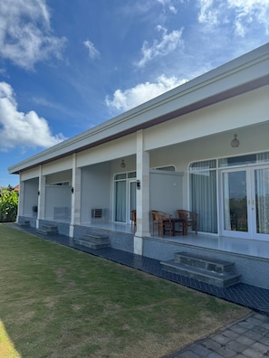 A modern house with a covered porch, large sliding glass doors, and a well-maintained lawn.