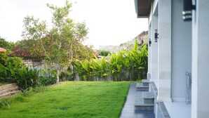 A modern building with a flat roof, a well-maintained lawn, and a bamboo fence.