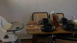 Ein Essbereich mit einem Holztisch, gedeckt für vier Personen, einem Hochstuhl und drei gerahmten Kunstwerken an der Wand.