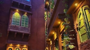 A traditional building with ornate wooden doors and windows, featuring intricate carvings and a warm, inviting atmosphere. - Partap Mahal (Bikaner)