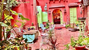 A courtyard with red walls, potted plants, and outdoor furniture. - Partap Mahal (Bikaner)