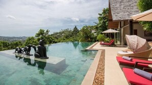 A modern infinity pool with clear water, surrounded by lounge chairs and a view of the landscape.