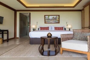 Una habitación de hotel con cama, lámparas de noche, una mesita y un sofá.