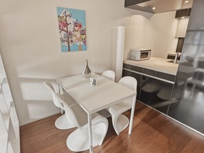 A modern kitchen with a white table and chairs, a microwave, and a refrigerator.