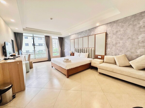 A modern hotel room with a large bed, a sofa, a desk, and a view of the outside. - LAGUNA Premier Hotel (Tan Hung)