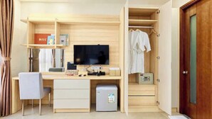 A compact bedroom with a wooden desk, a television, a small refrigerator, and a wardrobe. - LAGUNA Premier Hotel (Ho Chi Minh City)