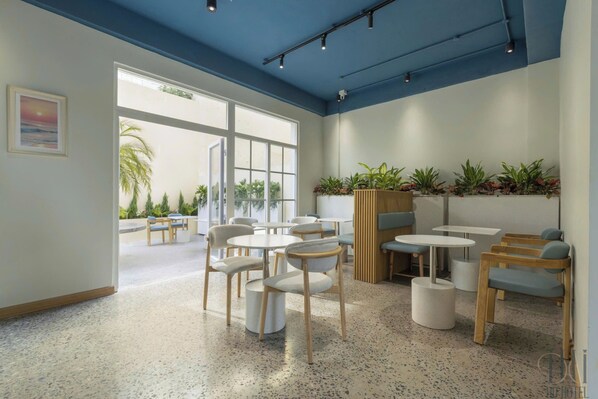 Un interior moderno con mesas y sillas redondas, ventanas amplias y plantas de interior.