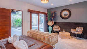 Een moderne slaapkamer met een groot bed, rieten meubilair en uitzicht op de omgeving.