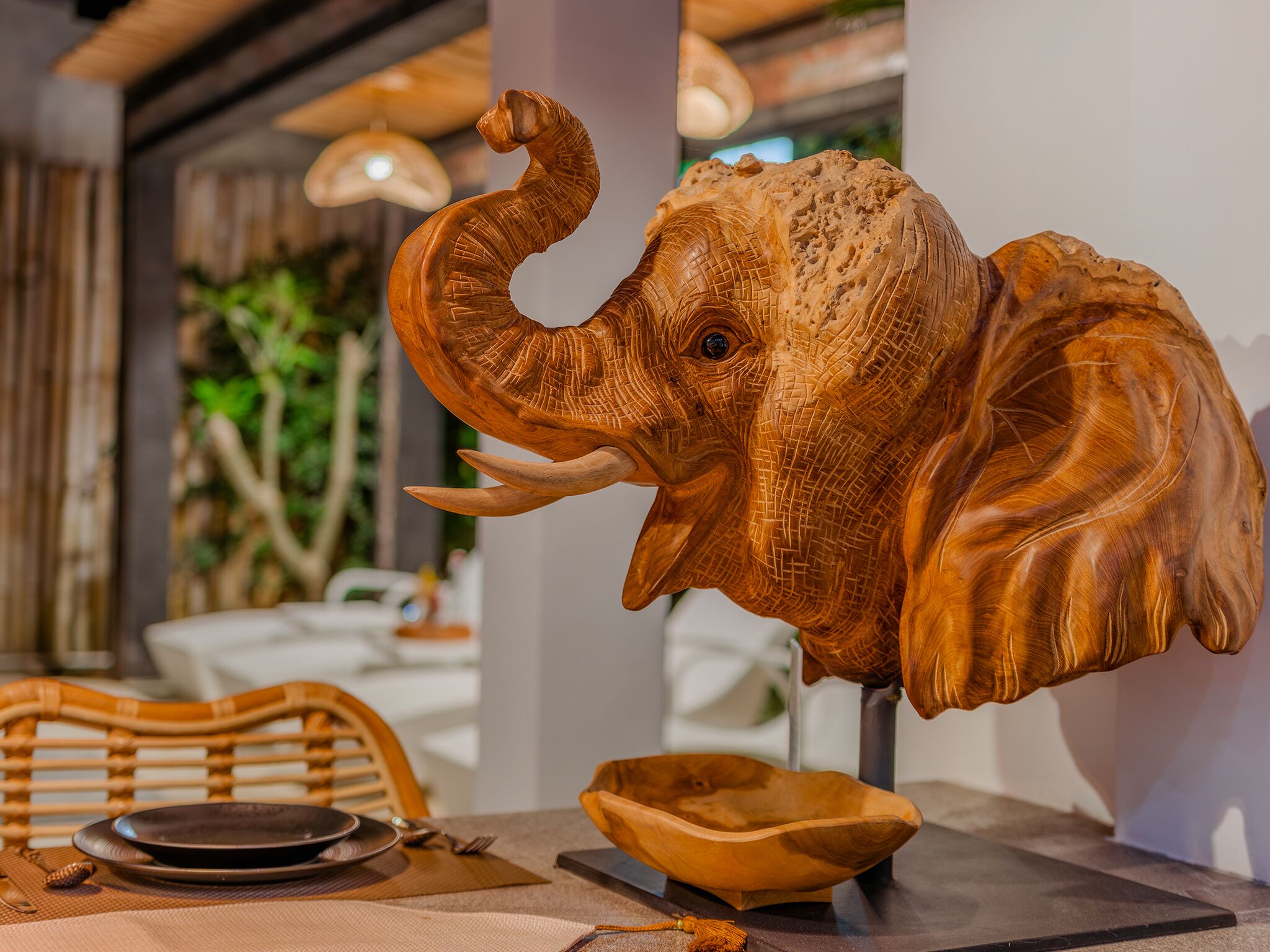 En træskulptur af et elefantshoved på et bord i en restaurant.