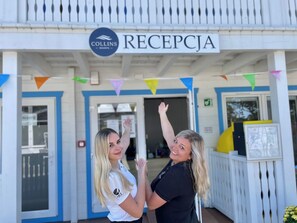 Un área de recepción con un letrero que dice "RECEPCJA" y el logotipo de "COLLINS RESORTS".