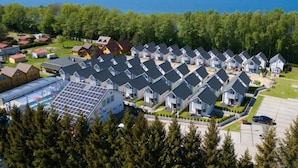 A residential area with multiple houses, a large solar panel installation, and a view of the ocean. - Collins Holiday (Sianożęty)
