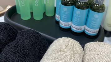 Un plat amb ampolles de xampú i gel de bany, i tovalloles beiges i negres.