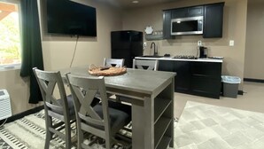 Een kleine keuken met een eethoek, een flatscreen televisie en een magnetron.