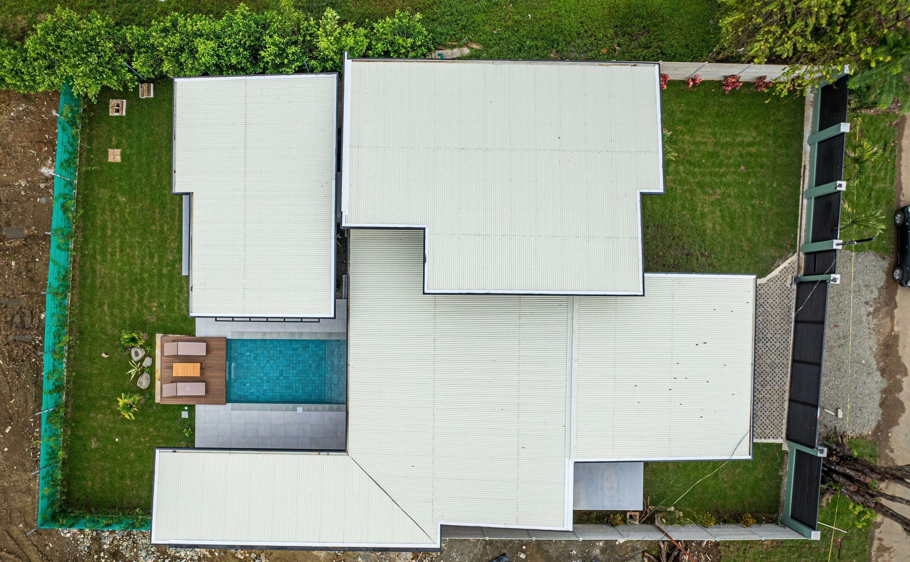 Vista aérea de um edifício moderno com várias seções, piscina e área cercada.