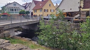 A bridge over a stream with houses in the background.
