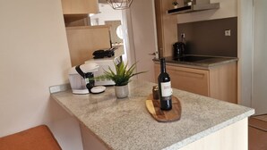 A kitchen with a countertop, a wine bottle, a plant, and a coffee maker.