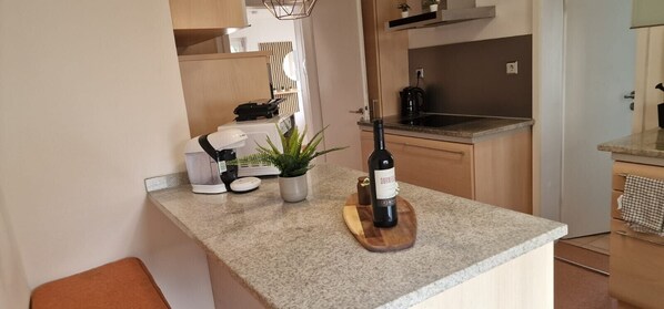 A kitchen with a countertop, a wine bottle, a plant, and a coffee maker.
