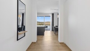 A modern interior with a wooden floor, a dining area with chairs and a table, and a view of the outdoors. - Maria Blick Lake View Apartments (Maria Woerth)