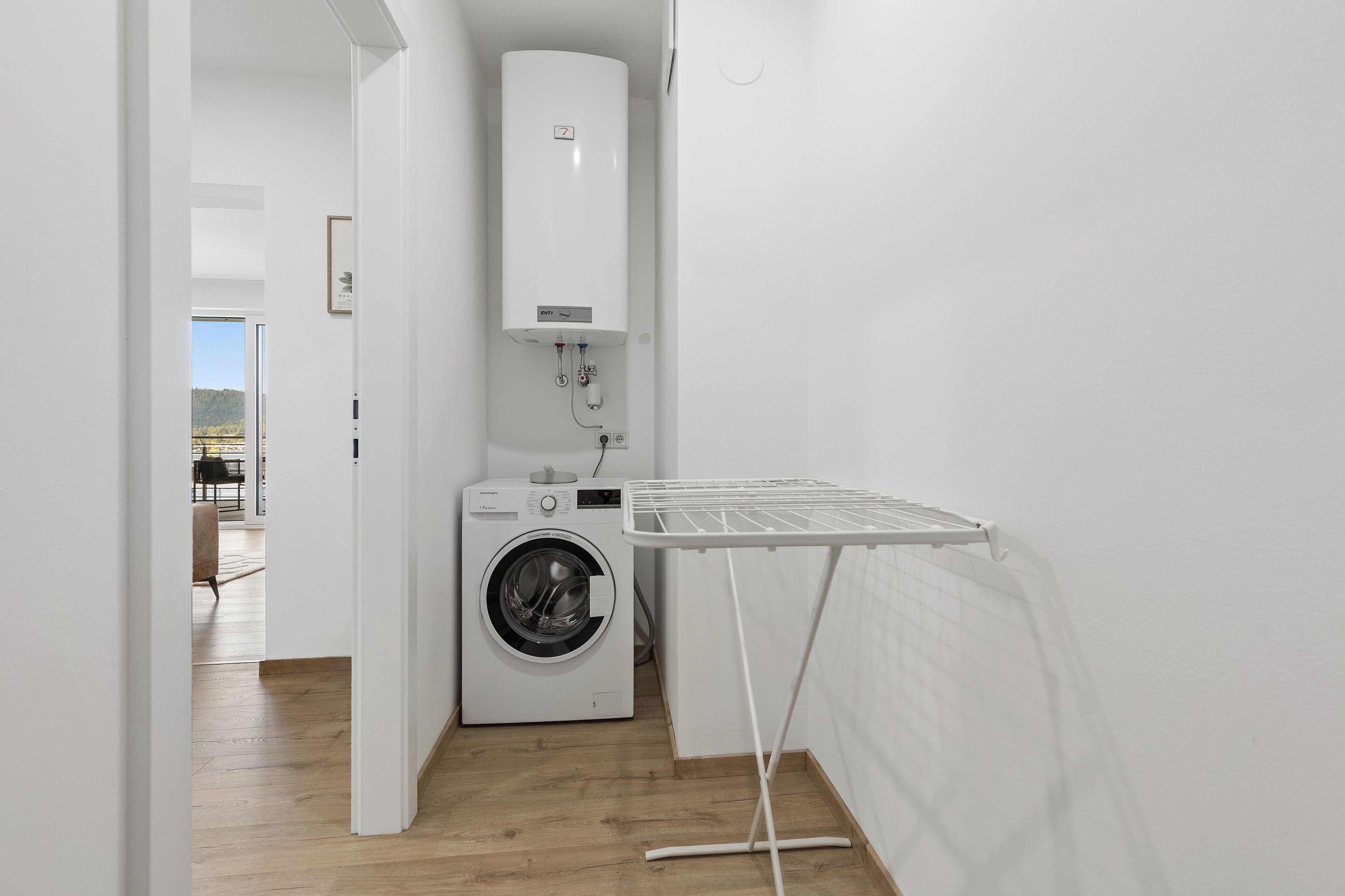 A laundry room with a washing machine, drying rack, and a water heater.