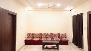 A room with a red sofa, a wooden table, and a ceiling fan.