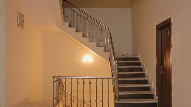 A staircase with a metal railing, a wooden door, and a light fixture on the wall.