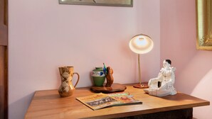 Una mesa de madera con un jarrón, una lámpara, una revista y una figurita.