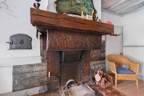 Een rustiek interieur met een open haard, rieten meubels en een deur in vintage stijl.