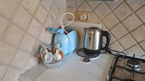 Une cuisine équipée d’une cuisinière à gaz, d’une bouilloire, d’un grille-pain et d’un porte-tasses.